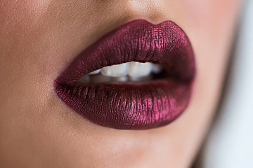 Closeup of beautiful woman lips with purple lipstick. Open mouth with white teeth. Cosmetics, lip...