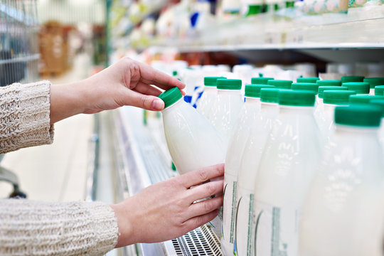 Woman Takes Bottle Of Milk From Shelf In Grocery