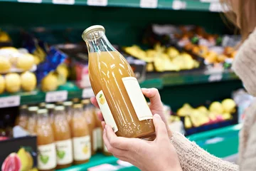 Papier Peint photo autocollant Jus Hands with bottle of fresh apple juice in store