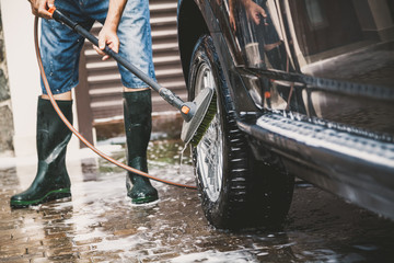 man washes modern car in  yard