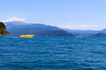 Motorboats boating on Lake Garda with mountain panorama, Italy