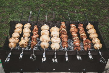 Skewers with meat and mushrooms are laid out on grill