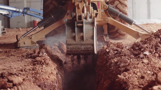 An Excavator Digs Red Dirt Out Of A Trench At A Construction Site