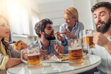 Happy friends eating pizza and watching tv at home