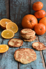 Homemade vegetarian orange cookies with organic oranges and clementines on shabby blue wooden board