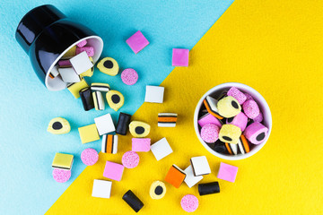 top view of colorful liquorice allsorts spilling from a cup