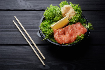 Asian or japanese salad in a plastic bowl or plate. Fast food concept with chopsticks. Healthy and fresh food. slice of red fish like salmon with lettuce and lemon. Copy space
