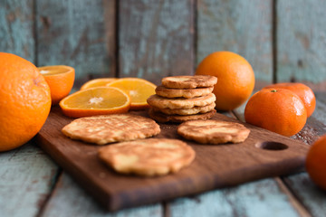 Vegetarian healthy sweets. Homemade tasty cookies with raw oranges and clementines on shabby blue wooden background