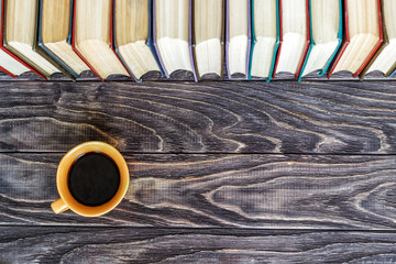 row of books cup with coffee on a wooden background with copy space, top view