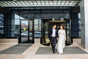 Smiling wedding couple walks out of the glass door - 197240057