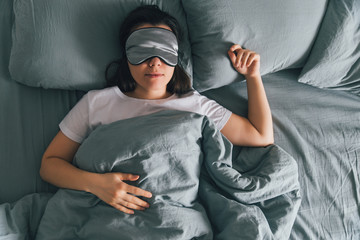 woman sleep in eye patch in grey bed. copy space - obrazy, fototapety, plakaty