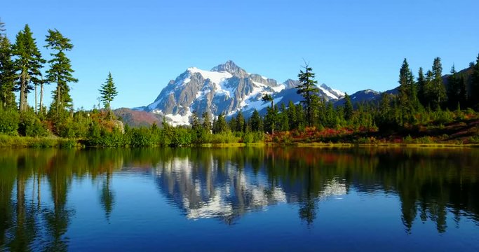 Scenic Mountain Lake With Still Water, Snowy Mountain Peak In Background, Surrounded By Towering Pine Trees - Picture Lake, Artist Point, Washington, USA - 4K Aerial Drone Footage Approaching Shot