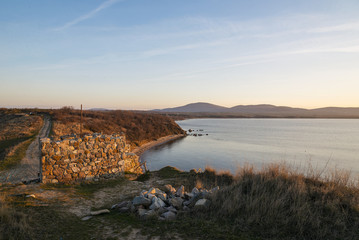 The tower of an ancient fortress on the beach. Winding coastline. Sunset.