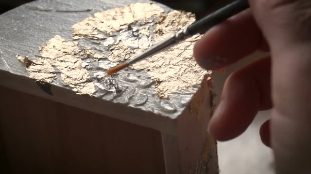 Applying Gold Leaf. The Artist decorates the box with a sheet of gold. Restoration of the interior