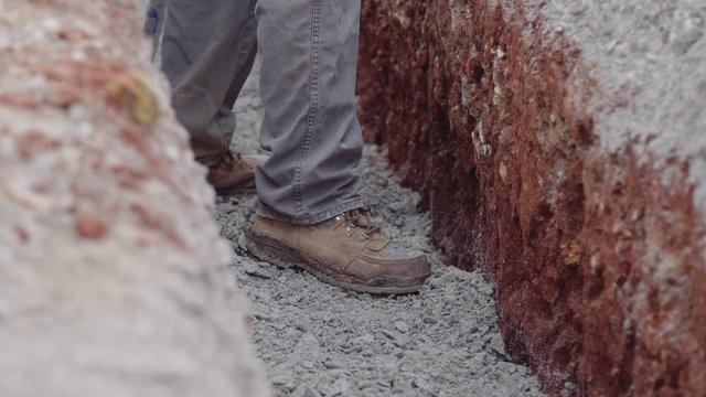 Construction Workers Spread Gravel Out Inside A Trench