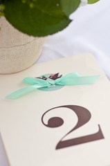 A tablet on the wedding table with number two and a turquoise ribbon