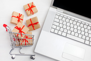 Paper boxes in a shopping cart on a laptop keyboard. Ideas about e-commerce, a transaction of buying or selling goods or services online.