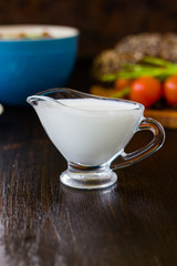 Natural cream dip in a glass bowl on dark wooden board.