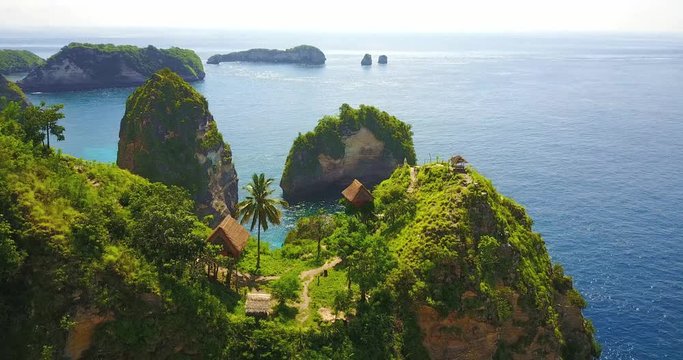 Aerial Fly Over View Of Multiple Tree House Hostels On Cliff Point Overlooking Tropical Bay In Nusa Penida, Indonesia