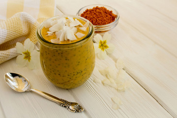 Pudding with chia,turmeric and coconut chips on the  white wooden background