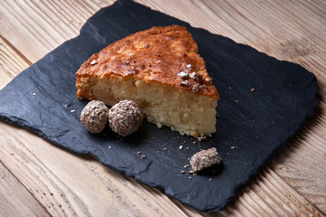 Apple pie tart on shale board with raisins, nuts and cinnamon is a vintage wooden background texture. Rustic style