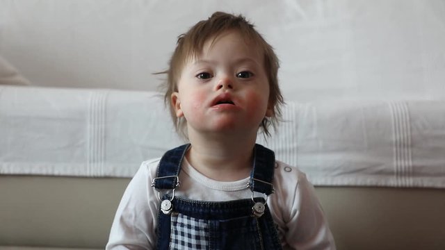 Portrait of cute baby boy with Down syndrome in home living room