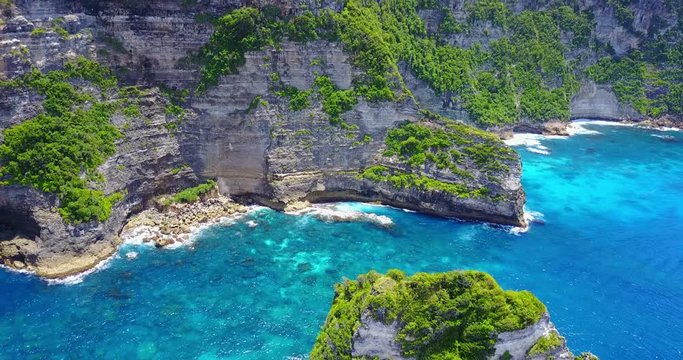 Nusa Penida Banah Cliffs - Aerial Approaching View Of Tropical Coast With Tan Rocky Cliffs Overlooking Turquoise Blue Cove