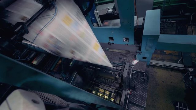 Dynamic camera motion of a printed newspapers rolling on printing equipment.