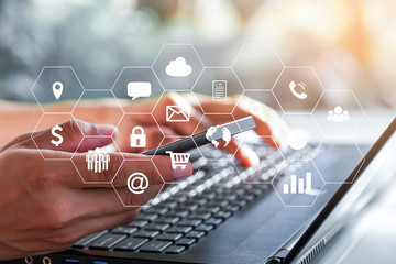 Businessman using smartphone and laptop and tablet computer with virtual icons interface.