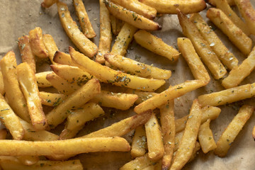 French fries with spices on paper, close-up.