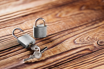 metal padlock with silvered keys on old wooden background. Estate and security concept with symbol of protection.