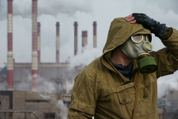 a man in a gas mask on a background of smoky pipes of a factory