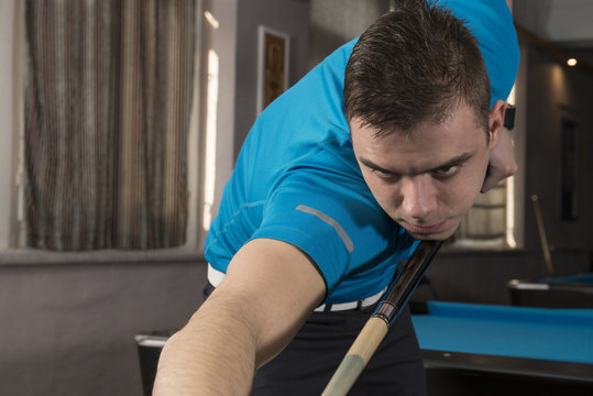 A close up of a billiard player in action, ready to play.