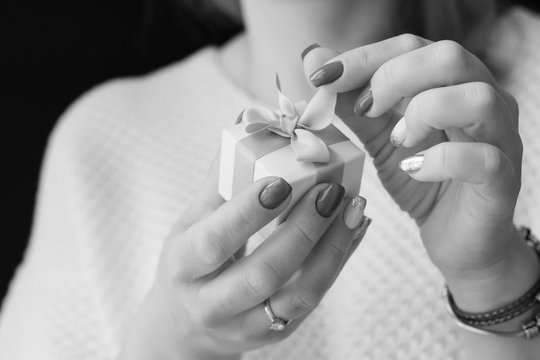 A woman with a beautiful fashionable manicure holds a white box with jewelery of a famous jewelry brand. The best gift for any celebration. Congratulations for her. Bracelet with charms.