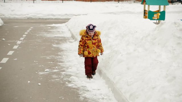 The child, a girl of 5-6 years, walks near the kindergarten.