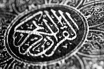 Black and white image of Islamic Book Quran with arabic calligraphy that means Al-Quran, the Holy Quran