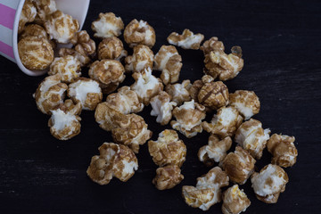 Sweet popcorn on the black background. Popcorn in the pink bucket. Snack for the movies. Cinema set.