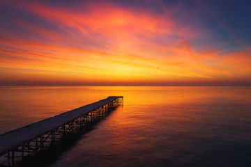 Aerial view over the old broken bridge in the sea, sunrise shot.