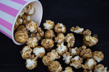 Sweet popcorn on the black background. Popcorn in the pink bucket. Snack for the movies. Cinema set.