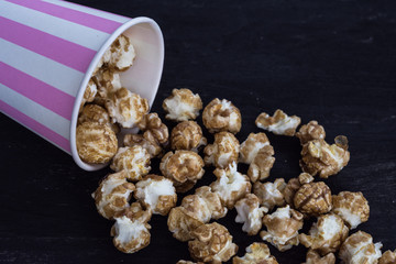 Sweet popcorn on the black background. Popcorn in the pink bucket. Snack for the movies. Cinema set.