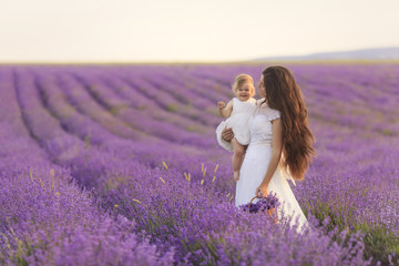 Happy beautiful mother and cute little daughter have fun in aroma lavender fields. Family holiday...