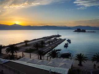 A panoramic view of the old harbour of Nafplio with the historical water castle of Bourtzi in the middle in sunset