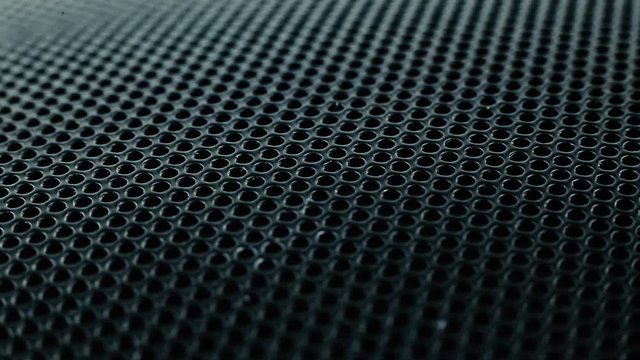 A metal mesh with round holes like a rotating background. Protective mesh speaker or subwoofer.