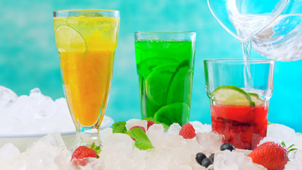 Preparing Summertime Spritzer drinks with fresh fruit, mango, berries, cucumbers and limes, with sparkling mineral water, on ice
