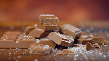 Sweet and salty chocolate snacks, salted caramel bar, macro close up on rustic wood background.