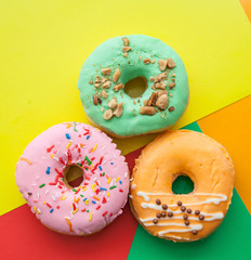 Three bright donuts on a colored background.