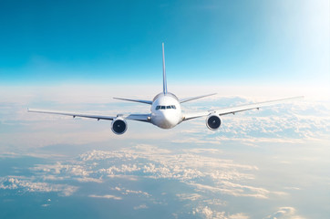 Naklejka premium Samolot pasażerski lecący na poziomie lotu wysoko na niebie ponad chmurami i błękitnym niebem. Zobacz dokładnie z przodu.