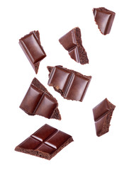 Pieces of porous chocolate falling close up on a white background