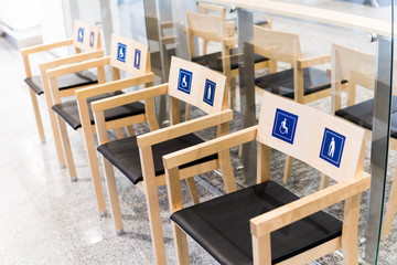 four wooden chairs at the airport with signs for the disabled and the elderly. Allocation of public seats to the disabled