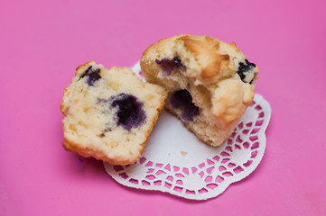 Fototapeta premium Close up of freshly baked blueberry muffin or cupcake on paper doily on pink tray with tulip for mother's day, a birthday party or tea time